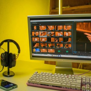 Modern home office setup featuring a monitor, keyboard, and headphones in a warm ambient lighting.